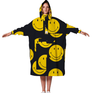 A person stands facing forwards with arms outstretched, wearing the oversized black Smiley hoodie decorated with bold yellow smiley face graphics and white trainers—an eye-catching Tallinn shopping find. Gate21.ee