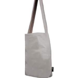 The Feel Good Bag - Feather Grey by Tinne+mia is a plain light grey shoulder bag with a long, wide strap and rectangular shape, shown against a white background. It features a small black tag on the side. Gate21.ee
