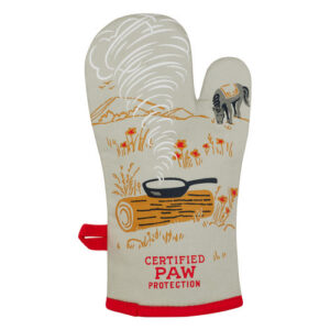 The “Boss kitty - Oven Glove” is a beige glove with red trim, showcasing a charming printed scene of a frying pan on a log with steam rising, surrounded by flowers and an adorable dog in the background. At the bottom, “CERTIFIED PAW PROTECTION” is printed in red, capturing the whimsical charm that BlueQ oven gloves are known for. Gate21.ee