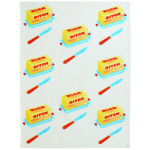 A white tea towel called “Rich Bitch” showcases a repeating pattern of yellow butter blocks labelled Rich Bitch, along with red and blue butter dishes and blue-handled red knives arranged in tidy rows, inspired by the whimsical designs of BlueQ oven gloves. Gate21.ee