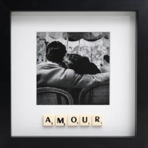 The LOVE - Scrabble Print features a black and white photo of a couple sitting close, viewed from behind, with Scrabble tiles spelling "AMOUR" beneath—framed in a black square to remind you of love’s special moments. Gate21.ee