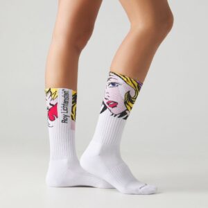 A person wearing Roy Lichtenstein Girl with Hair Ribbon - Athletic socks featuring a pop art blonde woman stands against a plain, light-coloured background. Gate21.ee