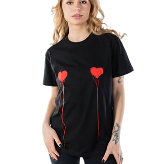 A woman with long, wavy hair models the LUKS - 1 Süda - T-shirt, a loose black tee with two red heart designs and line details, paired with black trousers—perfect for exploring a concept store. She poses against a plain white background. Gate21.ee