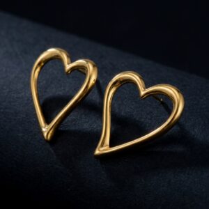 A pair of Love - BØLD Earrings in gold, featuring open-heart shapes, are displayed upright and side by side on a black fabric surface. Gate21.ee