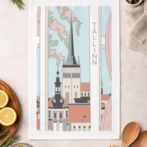 The Köögirätik – Vaade Tallinnale, a printed tea towel with an illustrated Tallinn cityscape, is displayed on a kitchen worktop with ingredients, utensils, a New Rebels small rucksack, strawberries, lemons, and seasonings. Gate21.ee