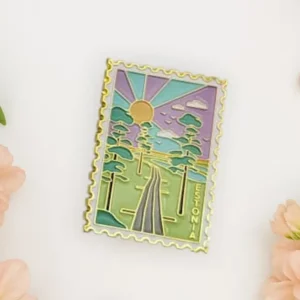 The "Magnet – hommik Viru rabas" features a scenic landscape with trees, a road, sunrise, pastel colours, and ESTONIA—surrounded by flowers and hearts. A perfect accessory for your New Rebels small rucksack. Gate21.ee