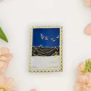 The "Magnet – talvine mets" is a rectangular enamel magnet styled like a postage stamp, featuring birds over a landscape with "Estonia" at the bottom, surrounded by pink flowers and hearts—perfect for pairing with your New Rebels small rucksack. Gate21.ee