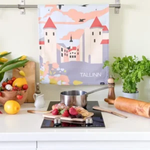 A modern kitchen worktop features a saucepan, strawberries on a chopping board, and a New Rebels small rucksack. Behind them hangs the "Köögirätik – Viru väravad" tea towel, with produce in a paper bag, potted herb, pepper mill, and rolling pin nearby. Gate21.ee