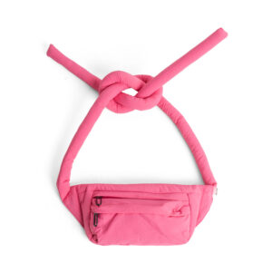 A red Knotflex Pack waist bag with long padded straps tied in a loose knot at the top, set against a plain white background. It features a zipped front pocket. Gate21.ee