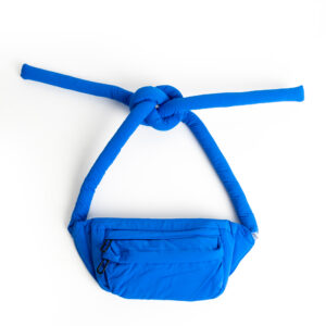A red Knotflex Rucksack with a front zip pocket and two long, padded straps knotted together at the top, displayed on a white background. Gate21.ee