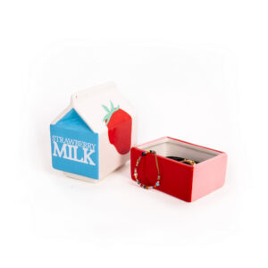 The Milk - Jewellery Box is a ceramic container shaped like a strawberry milk carton, lid off to reveal jewellery inside. It features a blue "Strawberry Milk" label and red strawberry art, reminiscent of Dreamy cat jewellery plate by Hello Ferretti. Gate21.ee