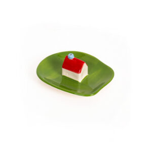 The Incense burner - Milk by Helio Ferreti features a small ceramic house with a red roof and blue chimney on a green, irregular plate, displayed against a white background. Gate21.ee