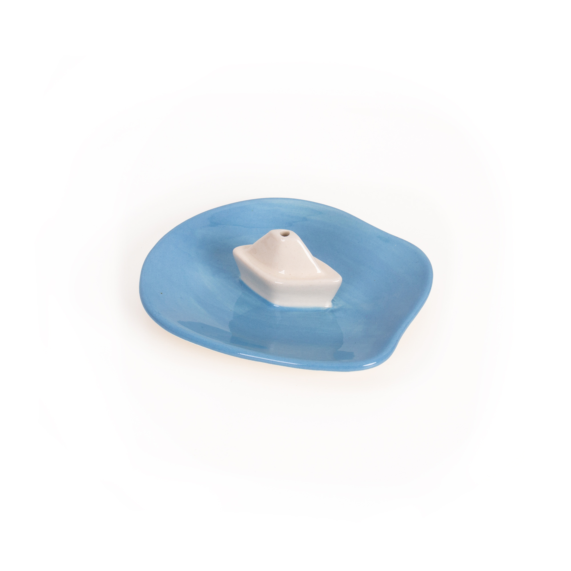 The Incense burner - House (Copy) is a small ceramic dish featuring an irregular blue base and a white geometric cone centre, inspired by Helio Ferreti’s modern, colourful designs, shown on a plain white background. Gate21.ee