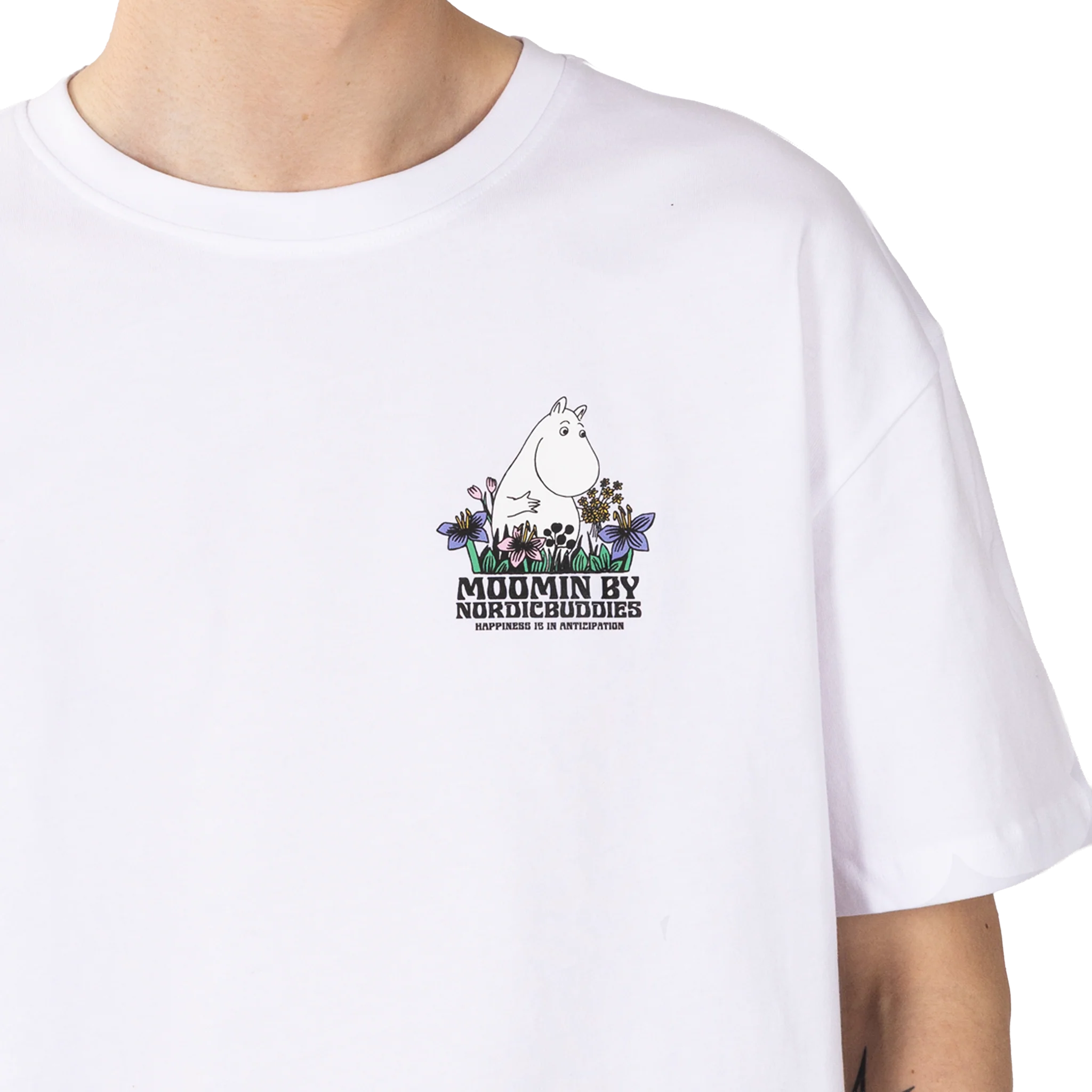 A person wearing the Moomin Ts - Meadow, a white T-shirt with a small Moomin character, flowers, and the text “MOOMIN BY NORDICBUDDIES HAPPINESS IS AN ATTITUDE” on the left chest. Gate21.ee
