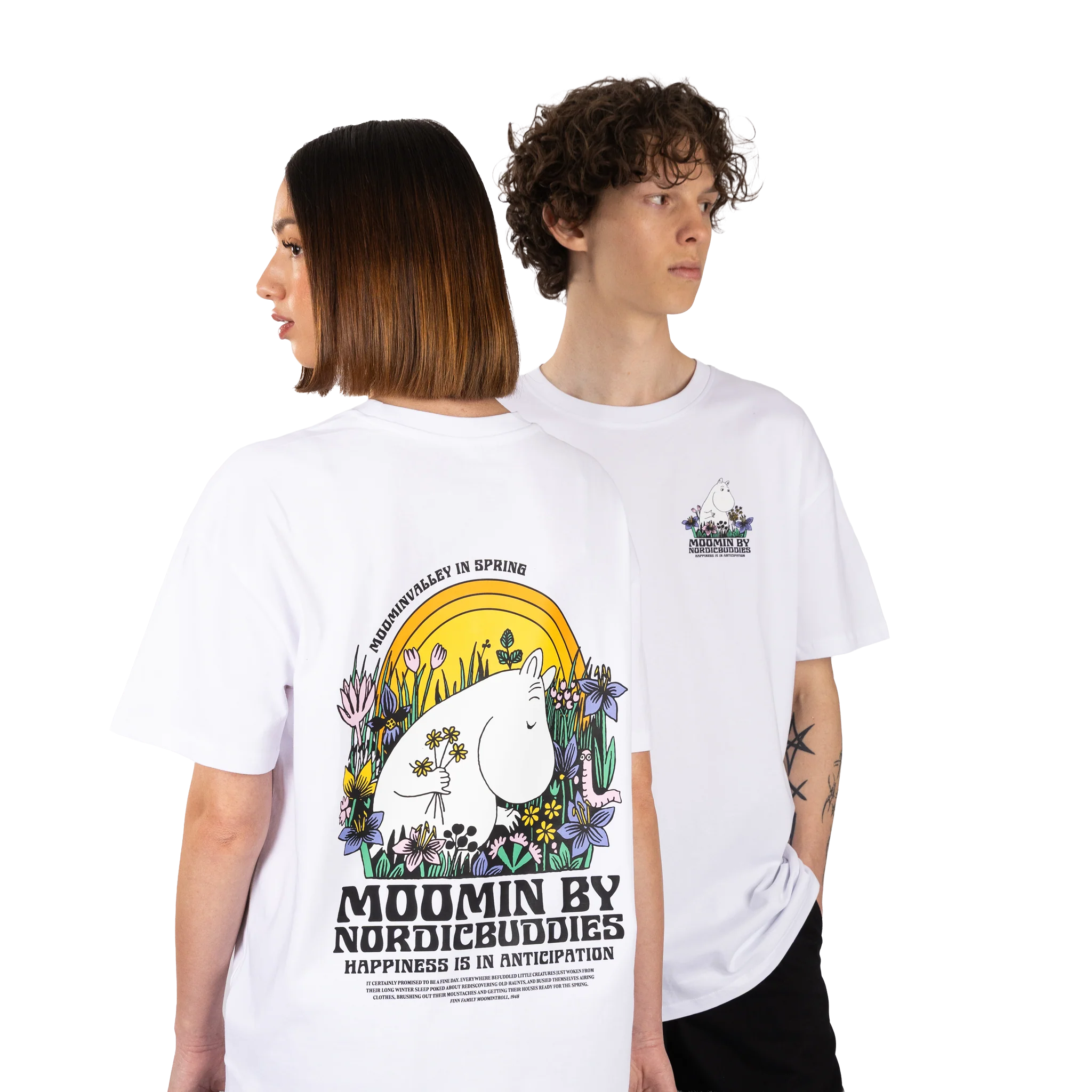 Two people wear Moomin T-shirts - Meadow. The shirts have a small Moomin graphic on the chest and a large, colourful Moomin illustration with flowers and text on the back. Gate21.ee