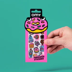 A hand holds a pink packet labelled "Criossant - Fabulous Stickers (Copy)" with a doughnut-shaped top, containing colourful sticker earrings and sweet treat designs like doughnuts, cupcakes, and ice cream against a teal background. Gate21.ee