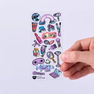 A hand holds a sheet of Heart - Fabulous Stickers (Copy), showcasing cartoon-style make-up items, eyes, lips, hearts, OMY sticker earrings, and phrases like SELF CARE and slay on a light purple background. Gate21.ee