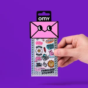 A hand holds a holographic envelope labelled "Donut - Fabulous Stickers (Copy)" against a purple backdrop. The pack displays colourful stickers such as OMY sticker earrings, with flowers, peace signs, and motivational phrases. Gate21.ee