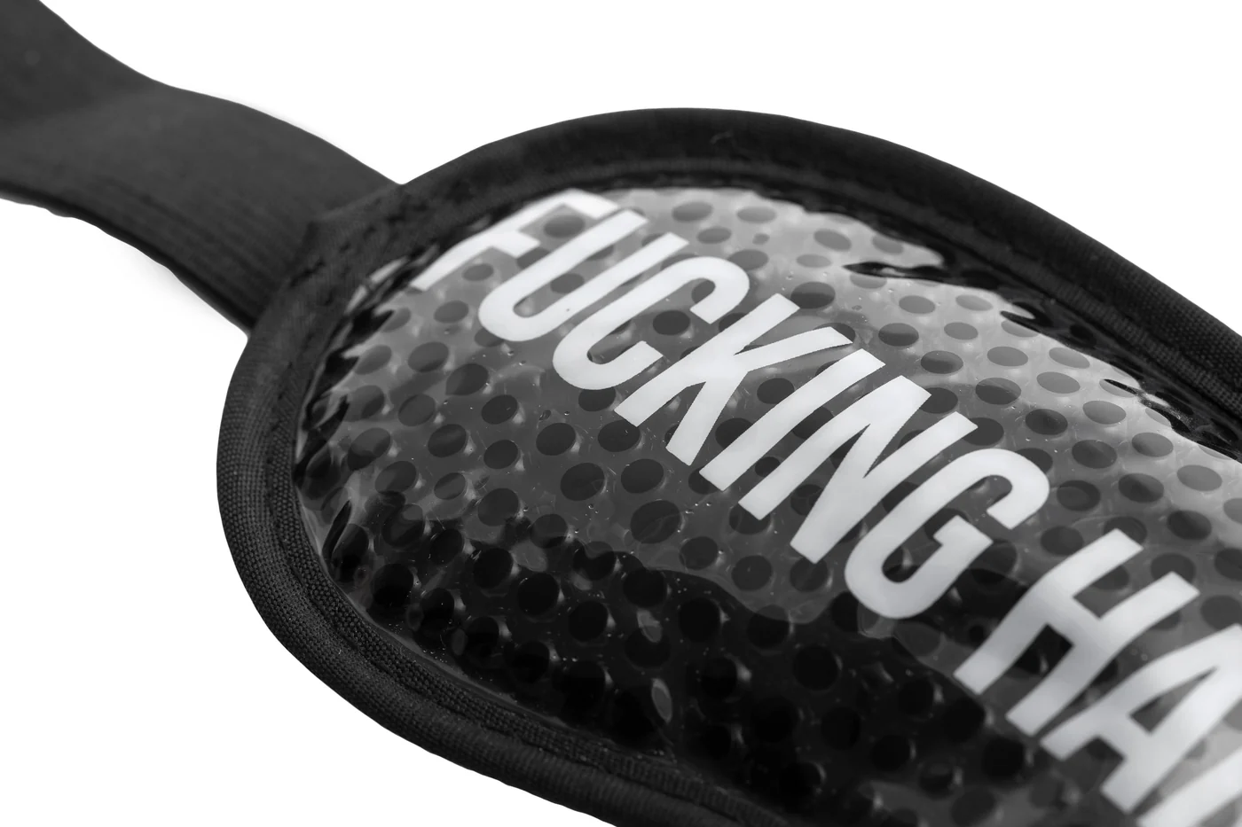 Close-up of the "Fucking Hangover" gel eye mask in black, featuring a textured, spotted surface and large white “FUCKING HA” text. The mask includes a fabric edge and strap—ideal for bright nights. Gate21.ee