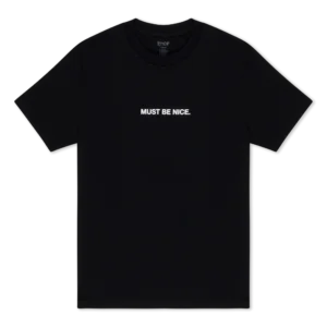 A plain black short-sleeve Coco Nerm T-shirt featuring "MUST BE NICE." printed in white capital letters across the chest. Gate21.ee