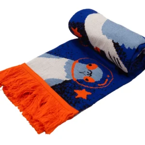 A rolled-up blue "Fox - Organic (Copy)" Kabak scarf featuring a woven otter with orange glasses, orange stars, and orange fringes at the ends. Gate21.ee