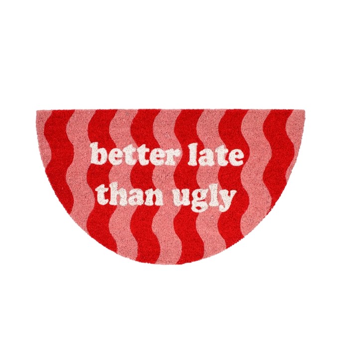 Aptly named the “Better Late than Ugly” doormat, this semicircular mat boasts eye-catching red and pink wavy stripes and displays the fun phrase in bold white lowercase letters across the centre—making it a standout piece to welcome guests with playful summer charm, especially when paired with your favourite handheld fan. Gate21.ee