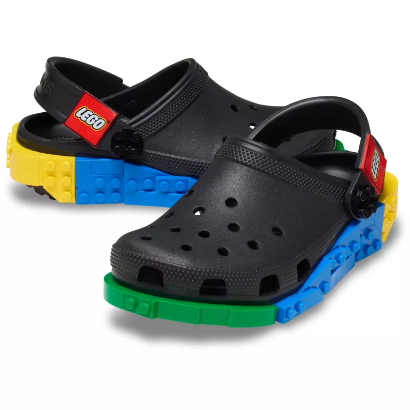 A pair of white Crocs™ 4LW System Clog sandals featuring multicoloured LEGO-style brick soles and red LEGO-branded heel straps. The sandals have ventilation holes on top and are displayed against a white background. Gate21.ee