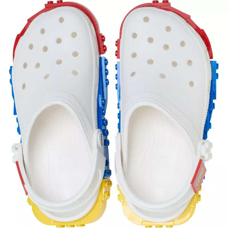 A pair of Crocs™ 4LW System Clog in white, featuring holes on the top and colourful building block-like attachments along the sides and soles, displayed from above against a white background. Gate21.ee