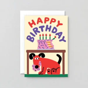 A birthday card from the Cake! - Greeting Card collection features a red dog eating cake under a table, with a birthday cake topped with candles and a missing slice sitting on the table above. “Happy Birthday” is written in colourful letters at the top. Gate21.ee
