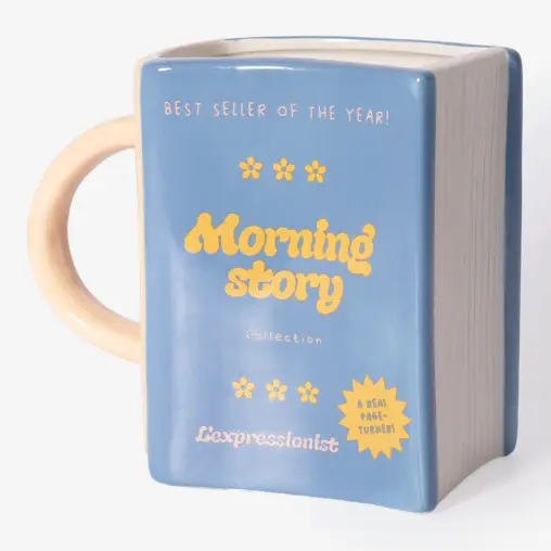 Introducing the Morning Story - Mug: a blue ceramic mug designed in the shape of a closed book, featuring a cream-coloured handle and edges. The front displays “Morning Story” in yellow text, accented with decorative flowers and additional white and yellow lettering. This unique piece is an ideal addition to any L’expressionist gift collection—perfect for book lovers who appreciate artistic flair. Gate21.ee