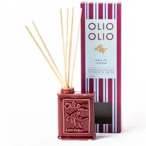 A ceramic diffuser resembling an olive oil can, labelled “Happy Cat - 100ml Diffuser,” holds reed sticks and brings a touch of home fragrance charm to your space. Next to it is a tall rectangular box labelled “Olio Olio Amalfi Lemon Fragrance Diffuser.” Both items are burgundy with white and gold details. Gate21.ee