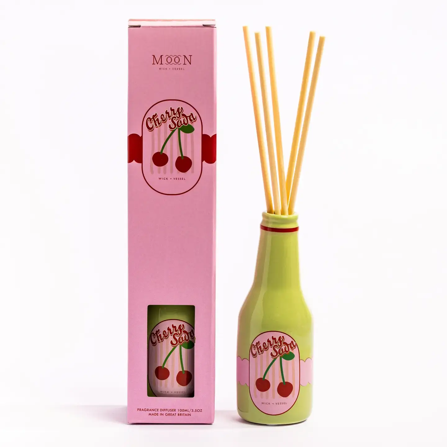 A pink box labelled Cherry Soda stands next to a green bottle with the same label. The bottle contains several reed diffuser sticks. Both items are set against a plain white background. Gate21.ee