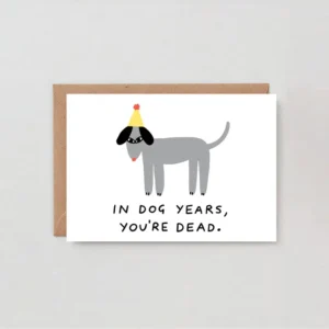 Dog Years! - Greeting Card features a cartoon grey dog in a yellow party hat and black glasses, with “IN DOG YEARS, YOU’RE DEAD” below. Arrives in a brown envelope—perfect for fans of fun wrap greeting cards. Gate21.ee