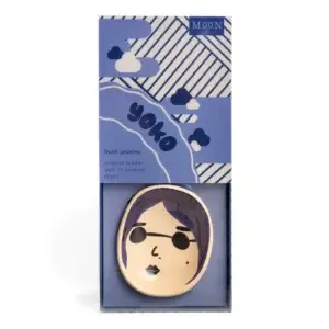 Yoko Faces - Incense Burner: This boxed incense holder features a charming cartoon face with purple hair, labelled “yoko.” Presented in packaging decorated with blue and white diagonal stripes and clouds, it reads “fresh jasmine incense holder with 25 incense sticks.” A playful addition to your Wick & Vessel home fragrance collection. Gate21.ee