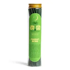 A clear tube with a gold lid holds green incense sticks labelled Lemongrass Dream Waves - 100 Incense Sticks. The design features a crescent moon, two palm trees, and product details in white and yellow lettering. This Wick & Vessel home fragrance is perfect for filling your space with tranquil vibes and enhancing any room. Gate21.ee