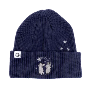 The Moomin Beanie - Navy is a dark blue knitted beanie showcasing two embroidered bears reaching for stars on the front turn-up, inspired by charming Moomin keyrings, with extra embroidered stars and a small white label on the left side. Gate21.ee