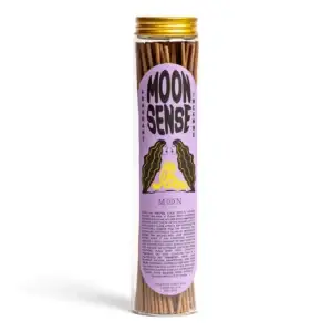 A clear jar with a gold lid holds 100 sandalwood incense sticks. The label reads “Moon Sense” and showcases a stylised design with a purple background, yellow figure, and black wavy elements. This unique home fragrance from Wick & Vessel is scented Moon Sense: Sandalwood. Gate21.ee