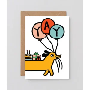 Front and centre on the “YYY! - Greeting Card” is a cheerful yellow dog holding three balloons that spell out YYY! in its mouth, while balancing a cake and colourful presents on its back. The card rests atop a brown envelope against a simple background—an ideal choice for anyone who enjoys sending greeting cards with charming, festive artwork. Gate21.ee